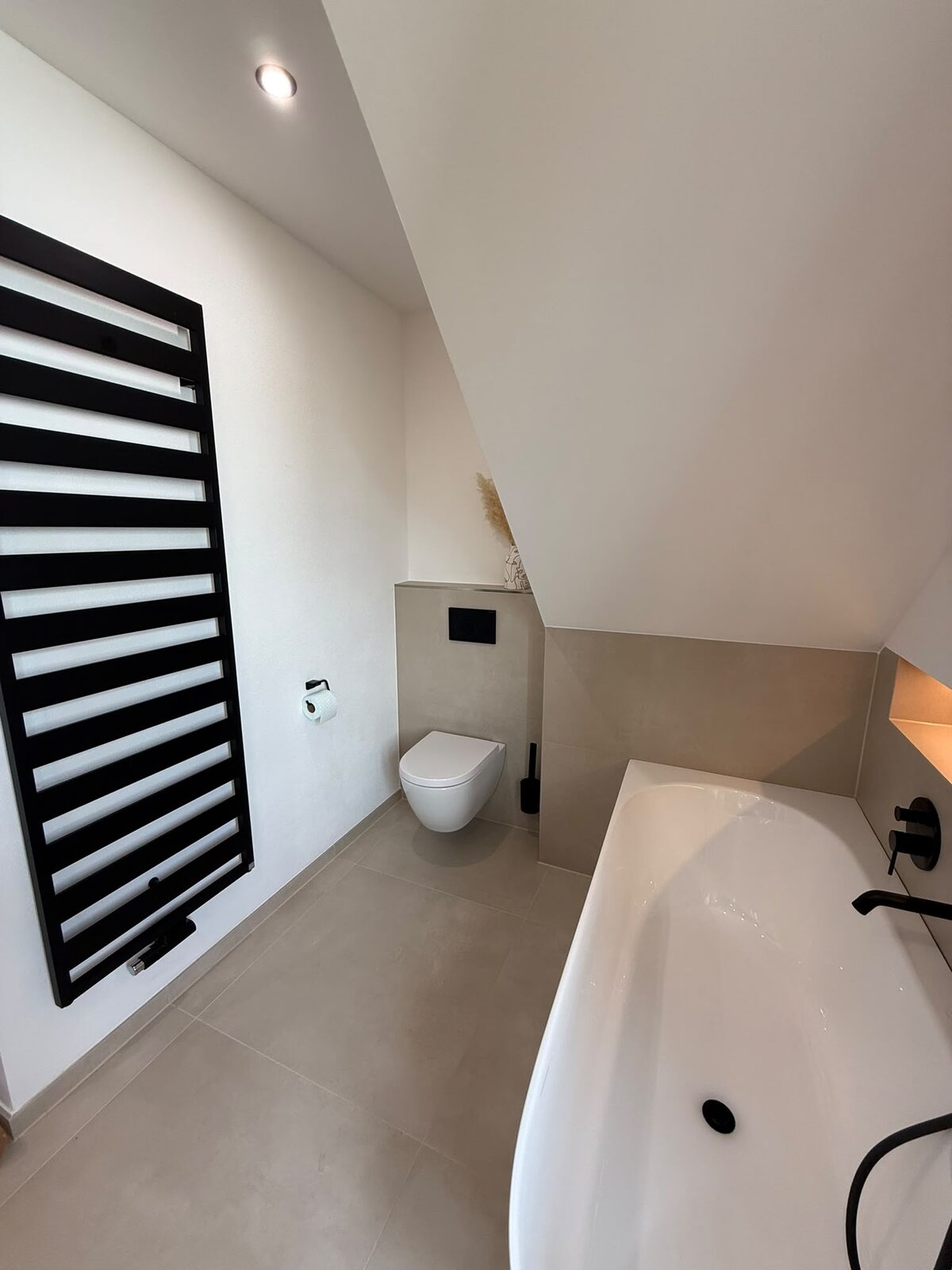 Dachbad mit Badewanne und schwarzem Handtuchheizkörper